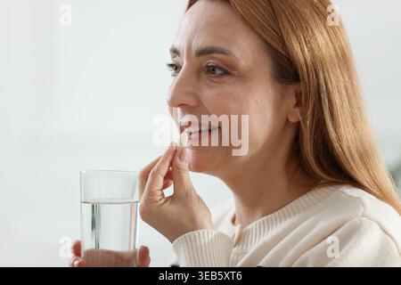 Menopause, hormone replacement therapy. Woman taking pill at home Stock Photo