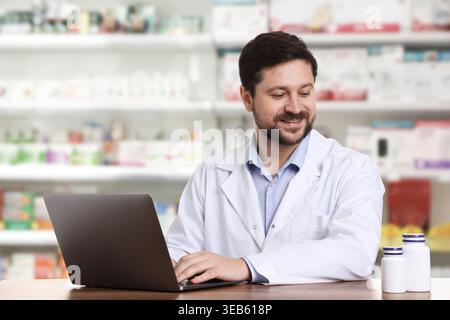 Pharmacist using laptop at table in drugstore Stock Photo