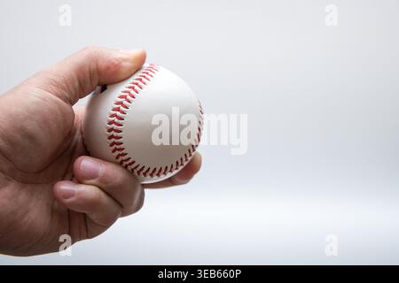 Hand holding baseball ball isolated on light background Stock Photo