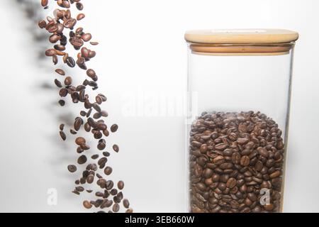 Coffee Beans Falling into Glass Jar on White Background Food and Freshness Concept Stock Photo
