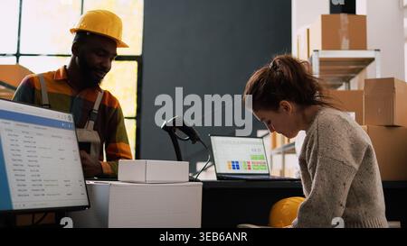 Supervisor inspecting cargo logistics in storage room, working on quality control with inventory list and barcodes. Two employees discussing about products verification in depot. Stock Photo