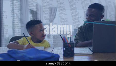 Working child in yellow T-shirt holding pencil at home, adult in dark sweater leaning over laptop Stock Photo