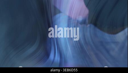 Flowing abstract curved form making sweeping blue and purple streaks in studio, with gradient bands Stock Photo