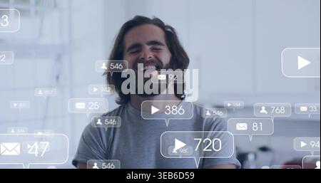 Laughing bearded man wearing grey tee in bright kitchen, bubbles and counters floating Stock Photo