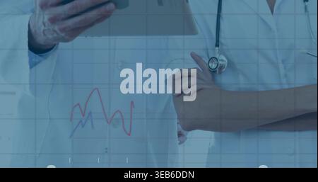 Reviewing clinicians in white coats examining tablet in clinic hall, with stethoscope, data overlay Stock Photo