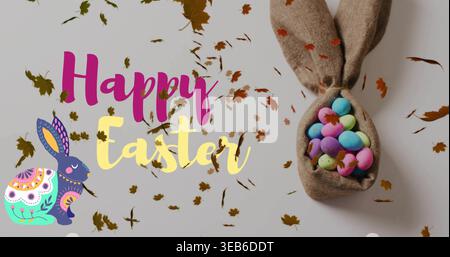 Showing bunny pouch holding pale speckled eggs on gray tabletop, with Happy Easter text, copy space Stock Photo