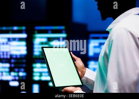 Manager examining server hub configuration settings using chroma key tablet. Supervisor meticulously analyzing event logs in monitoring software to pinpoint root cause of broken data center components Stock Photo