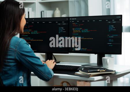 Young Asian in IT developer creating with typing online information on pc with coding program data of website application, wearing jeans shirt Stock Photo