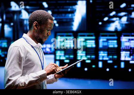 System administrator in server hub using renewable hydro energy sources to power cryptocurrency mining operations. Manager inspecting eco friendly supercomputers preventing environmental impact Stock Photo