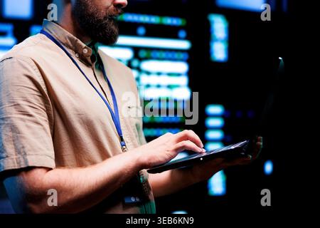 Precise technician doing checkup on interlinked computers creating server network. High tech establishment using parallel computing to perform complex computing operations and process data Stock Photo