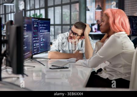 Software Engineer Quietly Fixes Broken Code While Stressed At Busy Desk. Stock Photo