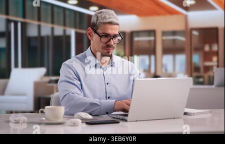 Focused Entrepreneur Using Laptop In Home Office Setting Stock Photo