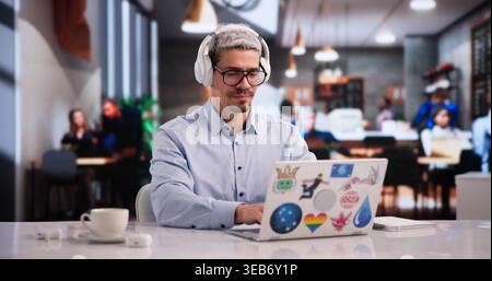 Determined Graphic Design Student Focused On Laptop In Lively Coffee Shop Stock Photo