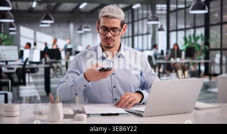 Hispanic Office Employee Capturing Document Image For Optical Character Recognition Using Mobile Device Stock Photo