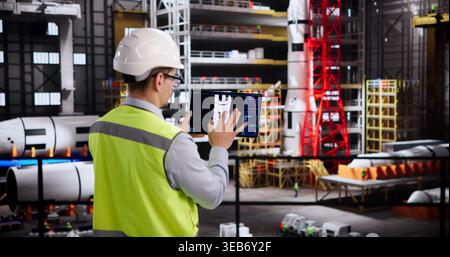 Hispanic Engineer Programs Cutting-Edge Automation Technology With Tablet Device Stock Photo