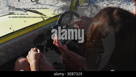 Using smartphone, woman wearing casual clothes leaning toward steering wheel in boat with overlays Stock Photo