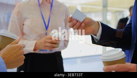 Exchanging business card, 3 professionals holding corrugated coffee cups at meeting, lanyard badge Stock Photo