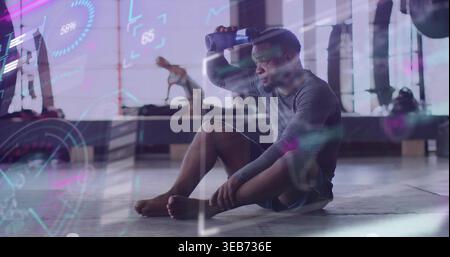 Holding water bottle to brow, seated man wearing sportswear resting in gym, bench HUD overlays Stock Photo