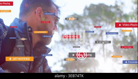 Looking man wearing glasses, padded jacket and backpack at park with floating UI badges, copy space Stock Photo