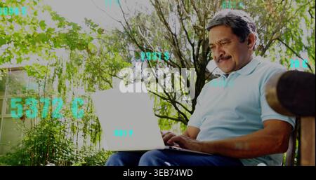 Typing older man blue polo on bench in garden with white laptop, teal graphics, copy space Stock Photo