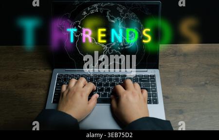 Business trends concept featuring a professional typing on a laptop with glowing neon text and a digital world map to symbolize international market r Stock Photo