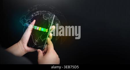 Business and technology trends concept. Hand holding smartphone with glowing neon text and a digital world map to represent global market analysis, mo Stock Photo