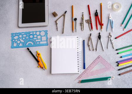 Top view of geometry tools, colorful pencils, and a blank notebook background. Professional drafting equipment, a stencil for creative engineering. Stock Photo