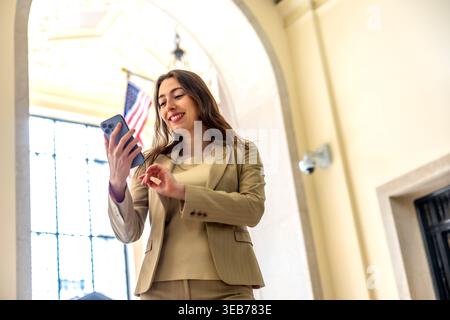 Business woman smiling using phone inside elegant nyc building Stock Photo