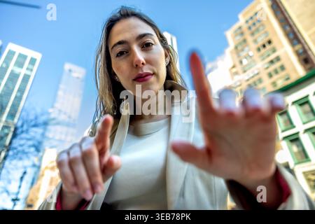 Businesswoman touching virtual screen in manhattan city street Stock Photo