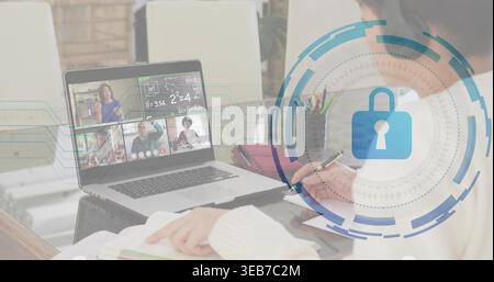 Writing woman in light sweater taking notes at home table, laptop, textbook, pen, digital lock Stock Photo