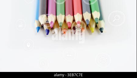 Displaying eleven sharpened colored pencils with tips down on white sheet, showing faint icons Stock Photo