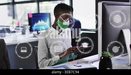 Tapping office worker in light button-up shirt holding tablet at office with monitor, digital icons Stock Photo