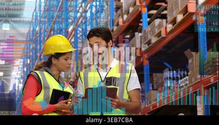 Reviewing inventory, two staff in hi-vis vests and hardhat checking tablet, noting notepad in aisle Stock Photo