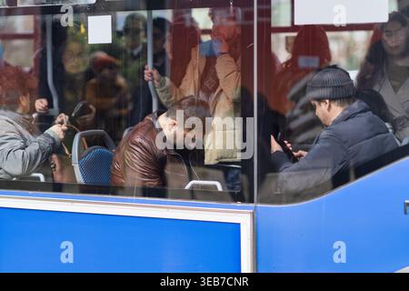 Batumi, georgia 21 april 2026: commuters aboard a batumi city bus, diverse passengers reflected in windows, capturing urban daily life and transit mov Stock Photo
