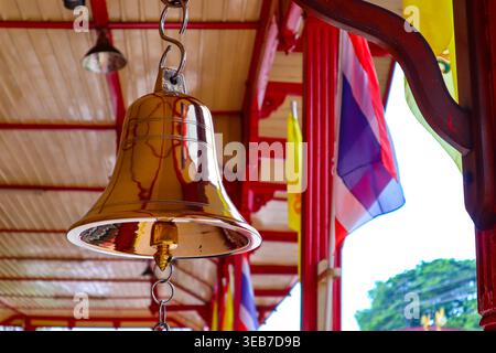 Gold bell on red wooden pole at the famous train station in Hua Hin. Selective focus on gold bell. Railway of Thailand. Stock Photo