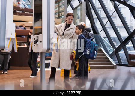 Batumi, georgia 21 april 2026: woman and schoolboy using a self-service ordering kiosk at modern mcdonald’s in batumi, georgia — mother assisting son Stock Photo