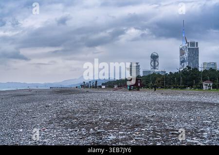 Batumi, georgia 21 april 2026: batumi's black sea pebble beach with a distant modern skyline on an overcast day, emphasizing coastal urban development Stock Photo