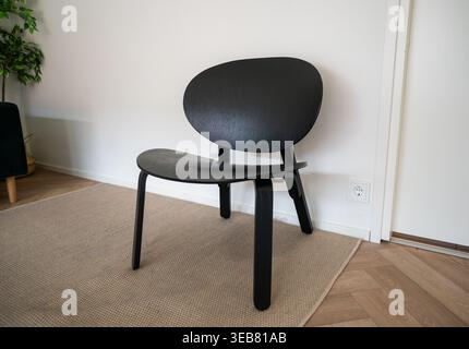 Modern black wooden chair in minimalist interior on carpet near white wall Stock Photo
