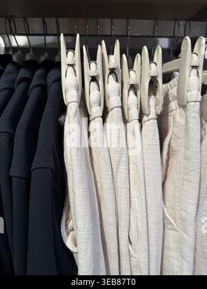 White fabric rolls stacked in a textile store display, showcasing material texture and color contrast. Mobile photo Stock Photo