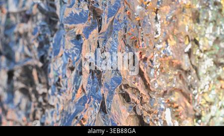 Crumpled aluminum foil texture with shining metallic surfaces and colorful reflections Stock Photo