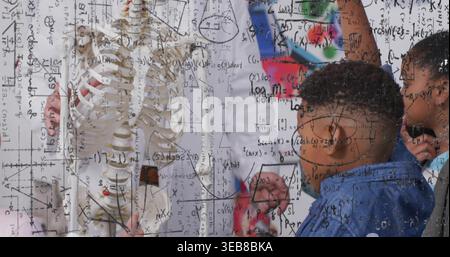 White-labcoat teacher showing skeleton behind marker glass, students in casual clothes school lab Stock Photo