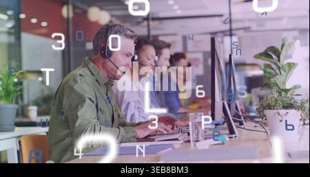 Working five call center agents in collared shirts, typing at long desk with monitors and headsets Stock Photo