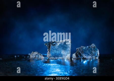 Broken ice with blue backlight on a dark background. Copy space. Stock Photo