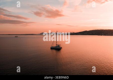 Aerial sailboat on rose gold bay at sunset near Antibes, France Stock Photo