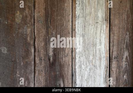 Reclaimed wood siding with brown weathered boards, strong wood grain, one worn white painted plank, gaps between boards, nail heads, screwheads, Stock Photo