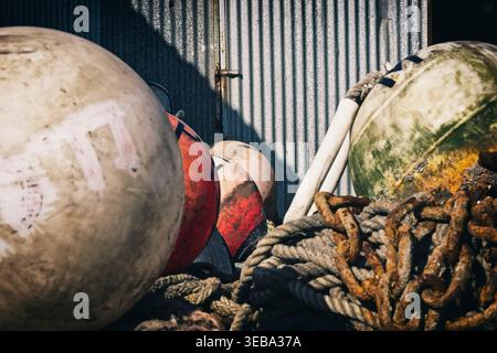 Large Round Buoys at Neyland Marina. In the foreground is a pile of old rope and rusty metal chains. Stock Photo