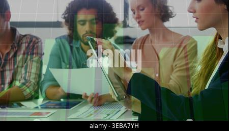 Tapping rightmost woman in dark blazer using tablet at table, reports, green overlay, copy space Stock Photo