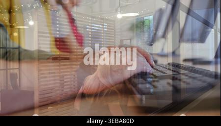 Typing close-up hands pressing keys on keyboard in modern office, with business-casual coworkers Stock Photo