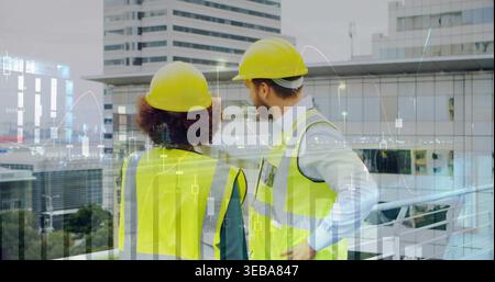 Two site engineers inspecting rooftop balcony, with data overlays, safety vests, yellow hard hats Stock Photo