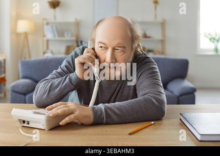 Serious Senior Man Talking On Phone Call At Home Stock Photo